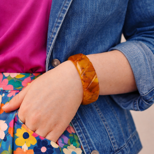 1940s carved Bakelite bangle in amber marbled tones worn on model wrist.
