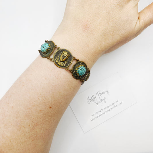 Styled image of antique Egyptian Revival bracelet with turquoise glass stones on wrist for display.