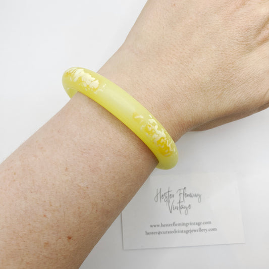 Vintage 80s yellow polymer bangle on wrist.