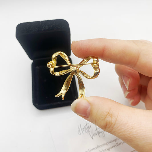 Back view of goldtone vintage ribbon brooch from the 1980s, styled for winter fashion