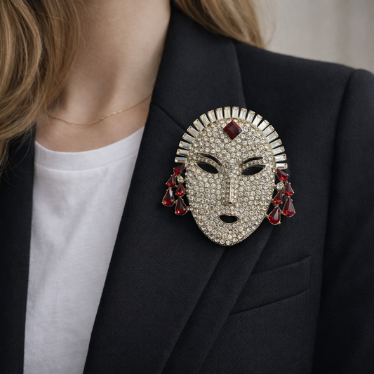 Butler and Wilson crystal mask brooch with ruby red accents on jacket