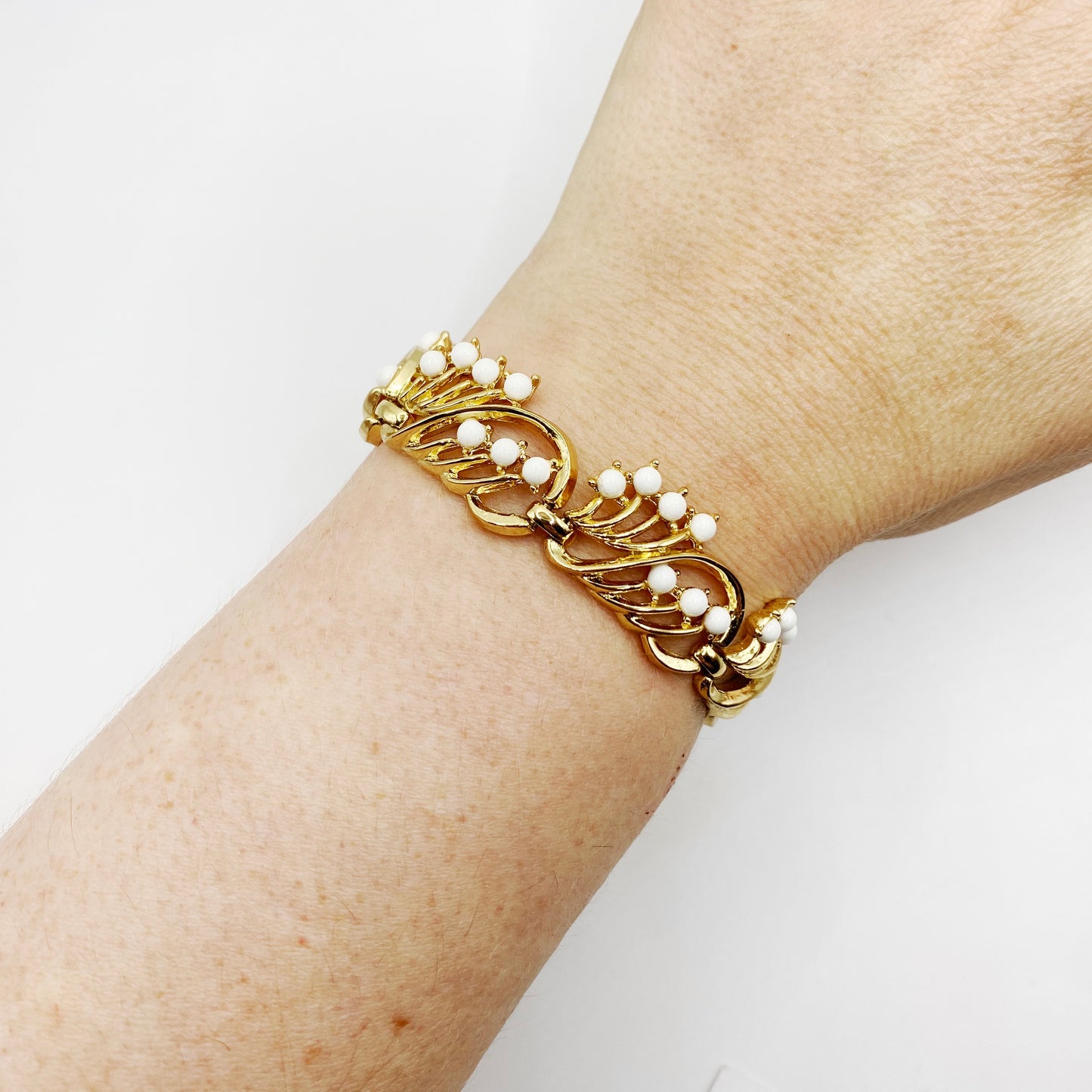Vintage Crown Trifari gold bracelet with white cabochons styled on wrist