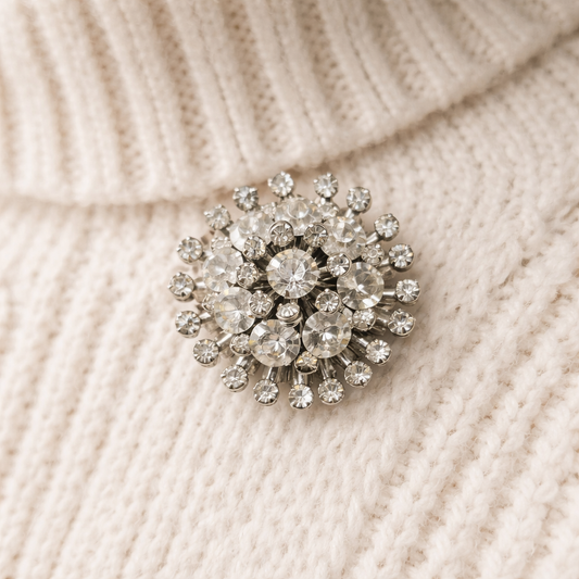 Mid century crystal rhinestone starburst brooch in silver tone setting on knit.