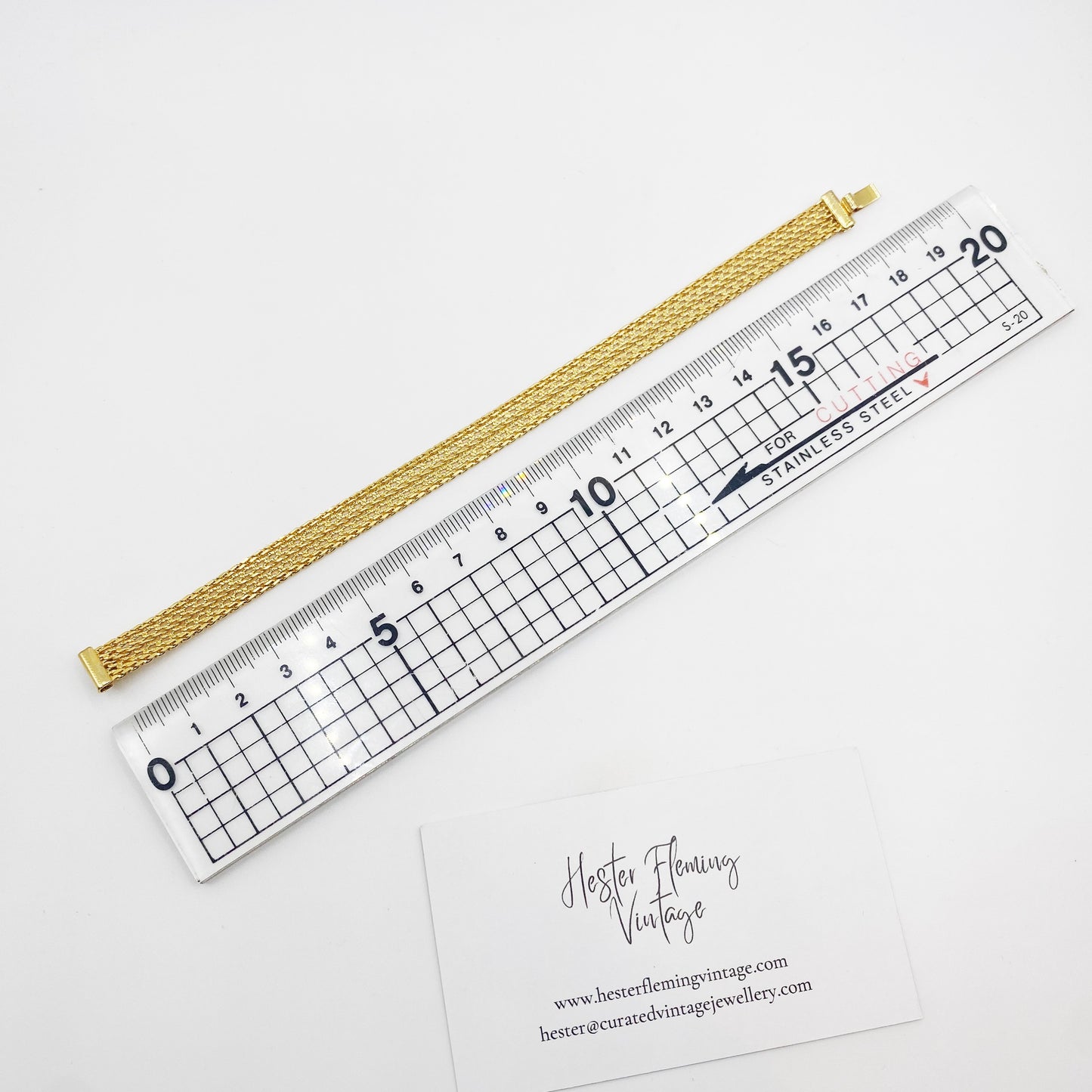 Flatlay of a vintage gold mesh bracelet from the 1970s, being measured against ruler.