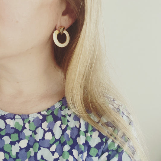 Model wearing 1970s vintage cream enamel and gold earrings – pierced style with retro elegance.