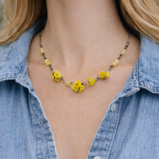 1930s Czech floral glass necklace worn by a model with denim. 