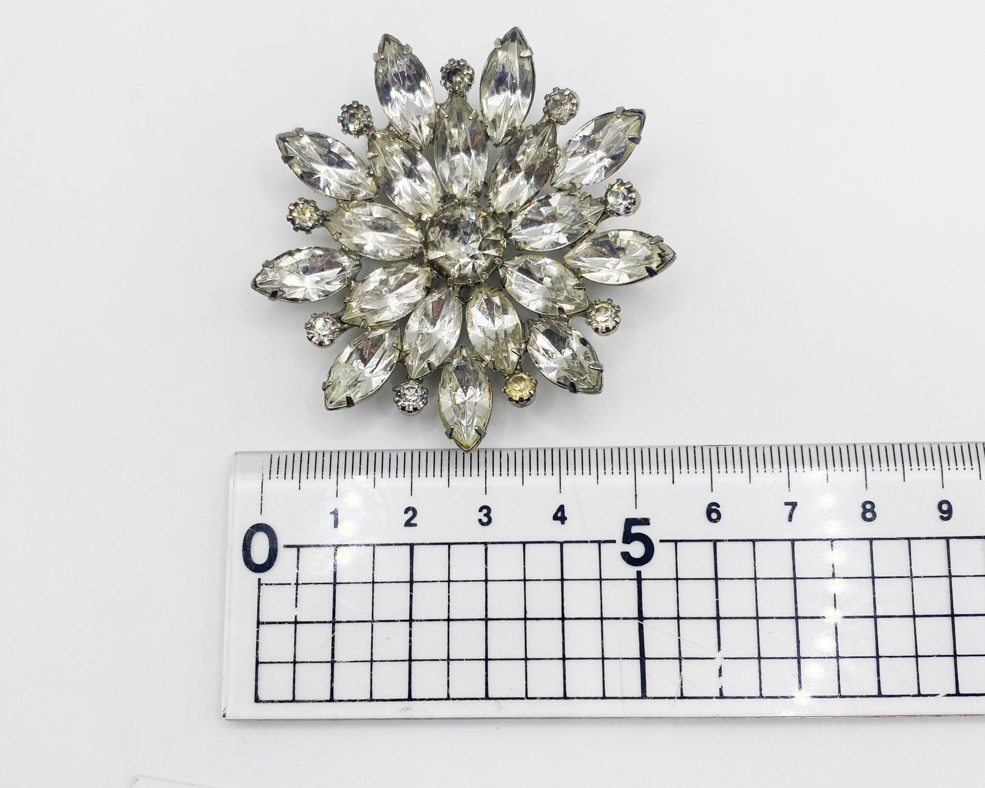 Vintage 1950s, crystal brooch placed next to a ruler for size. 