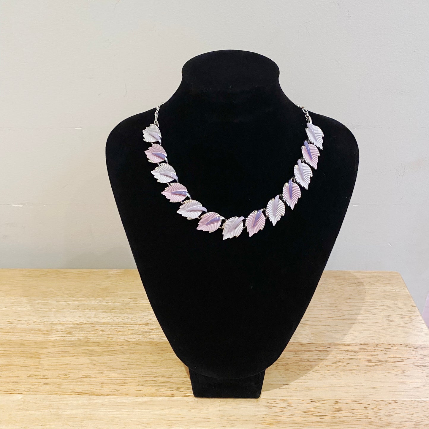1950s Enamel leaf necklace by Coro. Shown on a jewellery stand. 