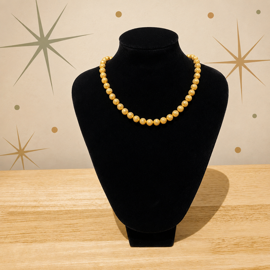 Gilt bead necklace by Trifari on velvet jewellery stand. 