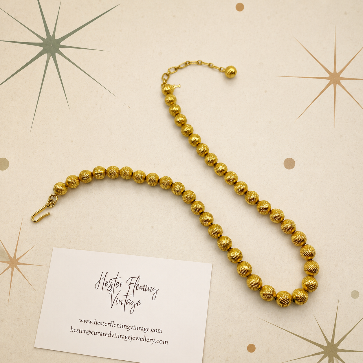 Gilt bead necklace by Trifari. Laid flat on mid century style background. 