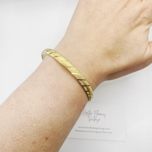 1960s Monet Gilt Bangle on wrist. Stripped design. 