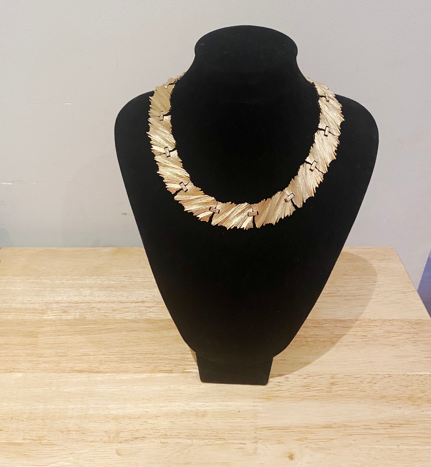 Close-up of Trifari 1960s textured gold-tone necklace on stand.