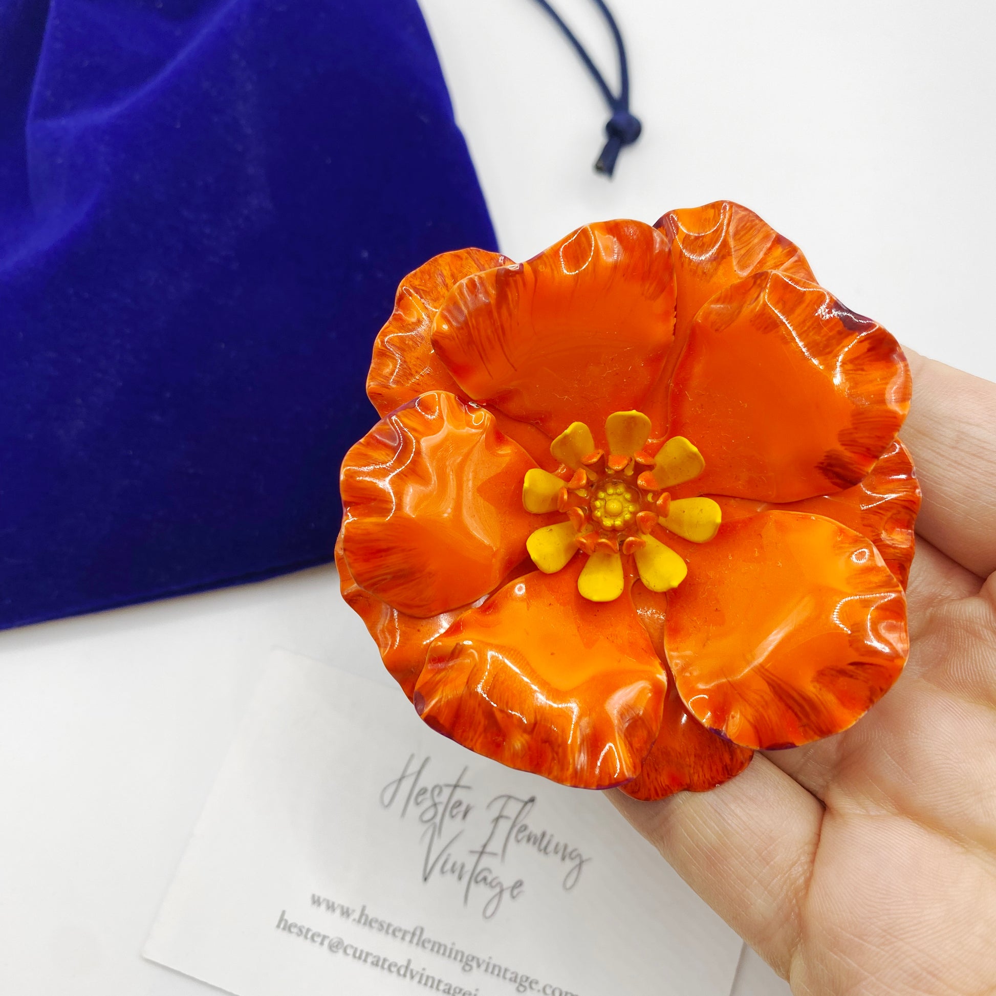 1960s Enamel Poppy Brooch placed on hand for scale. 