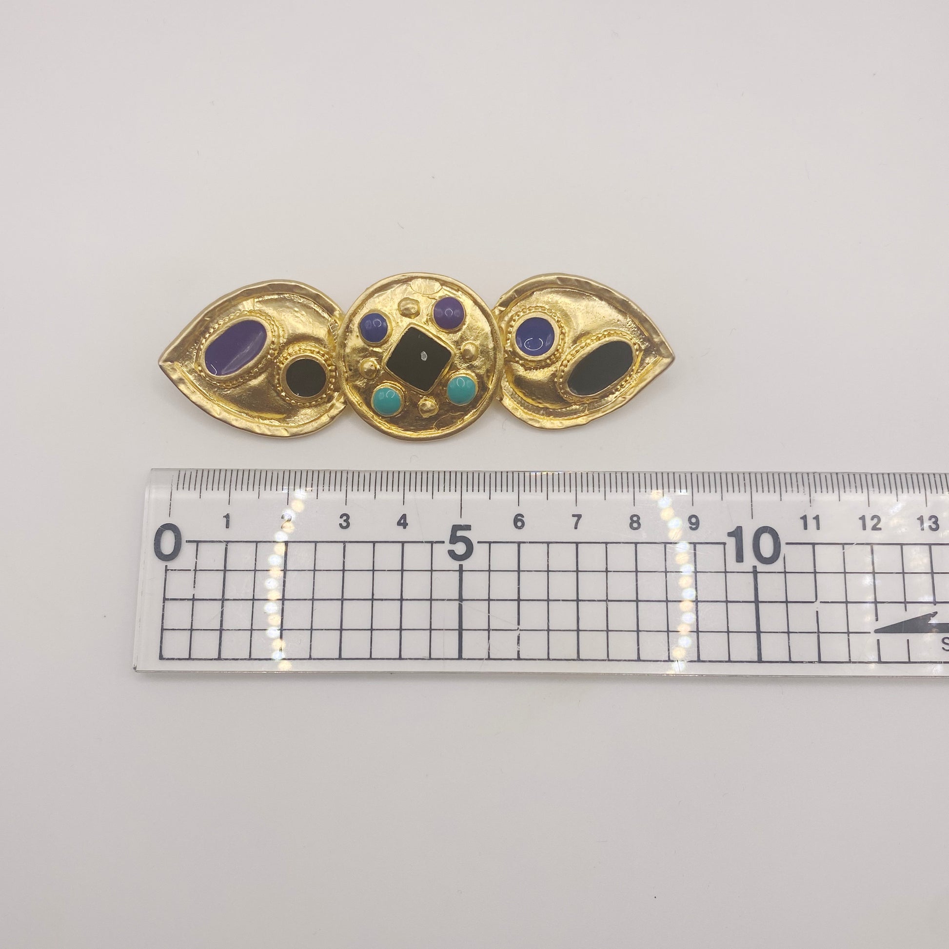 Measurement of enamel detailing on 1980s Egyptian Revival brooch, highlighting retro costume jewellery design.