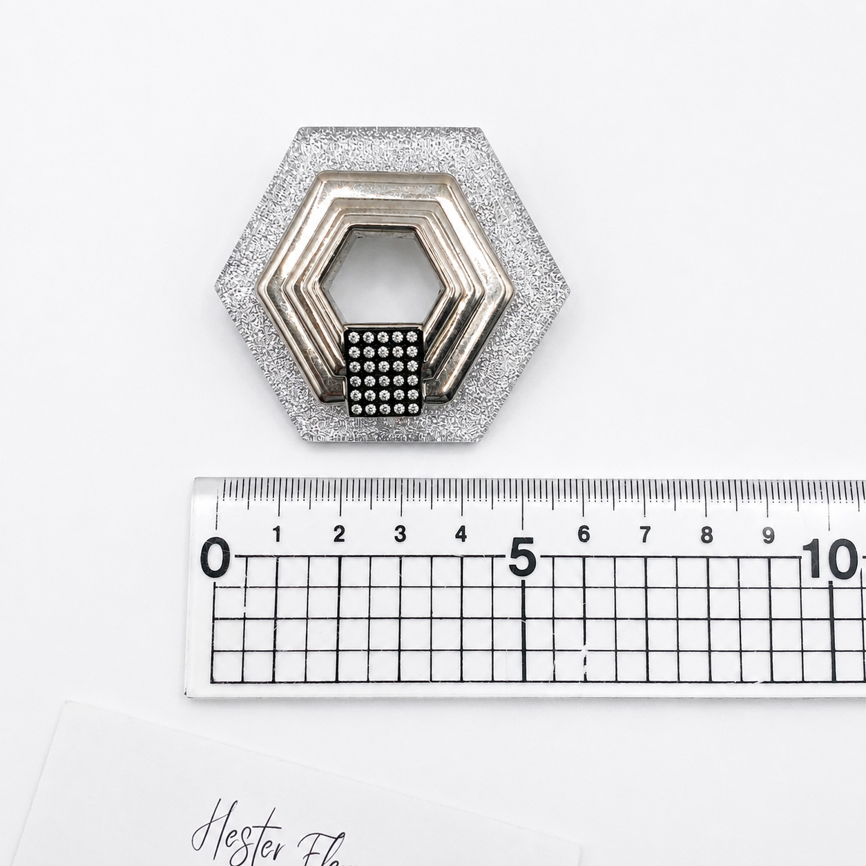Vintage 1980s French Art Deco brooch, placed next to a ruler for size.