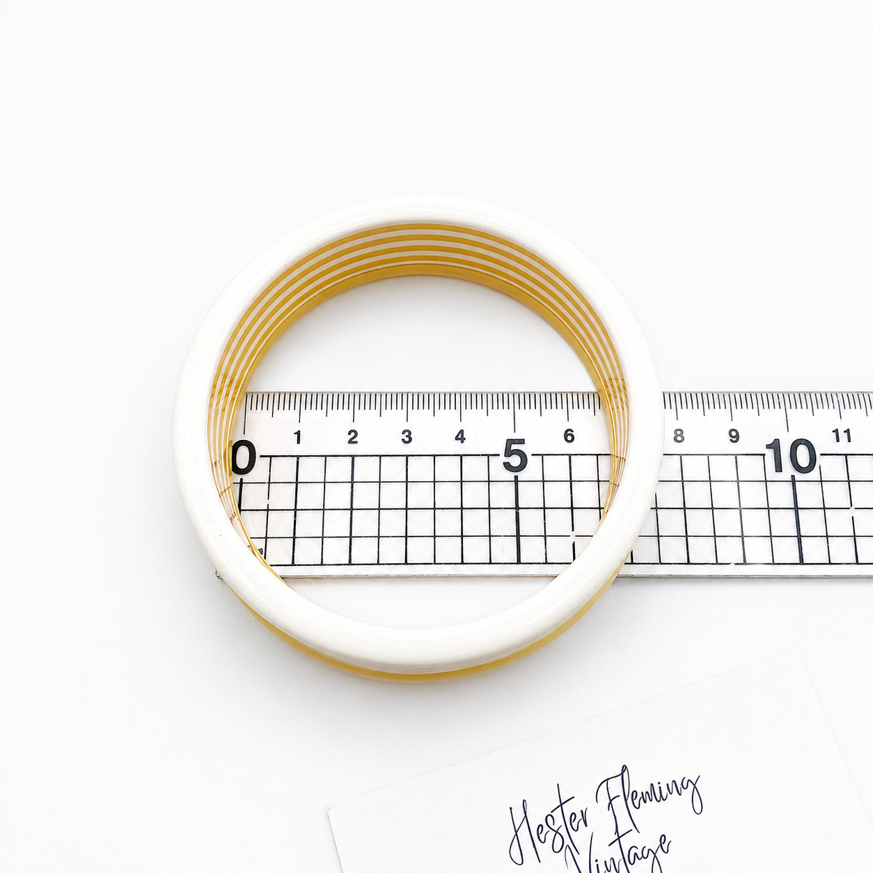 1980s French bangle set placed on a ruler for scale on a white background