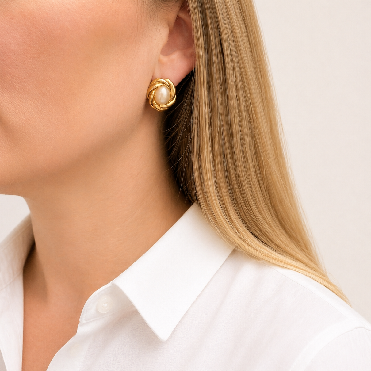 1980s Gilt knot and pearl earrings, styled on a model, wearing a crisp white shirt.