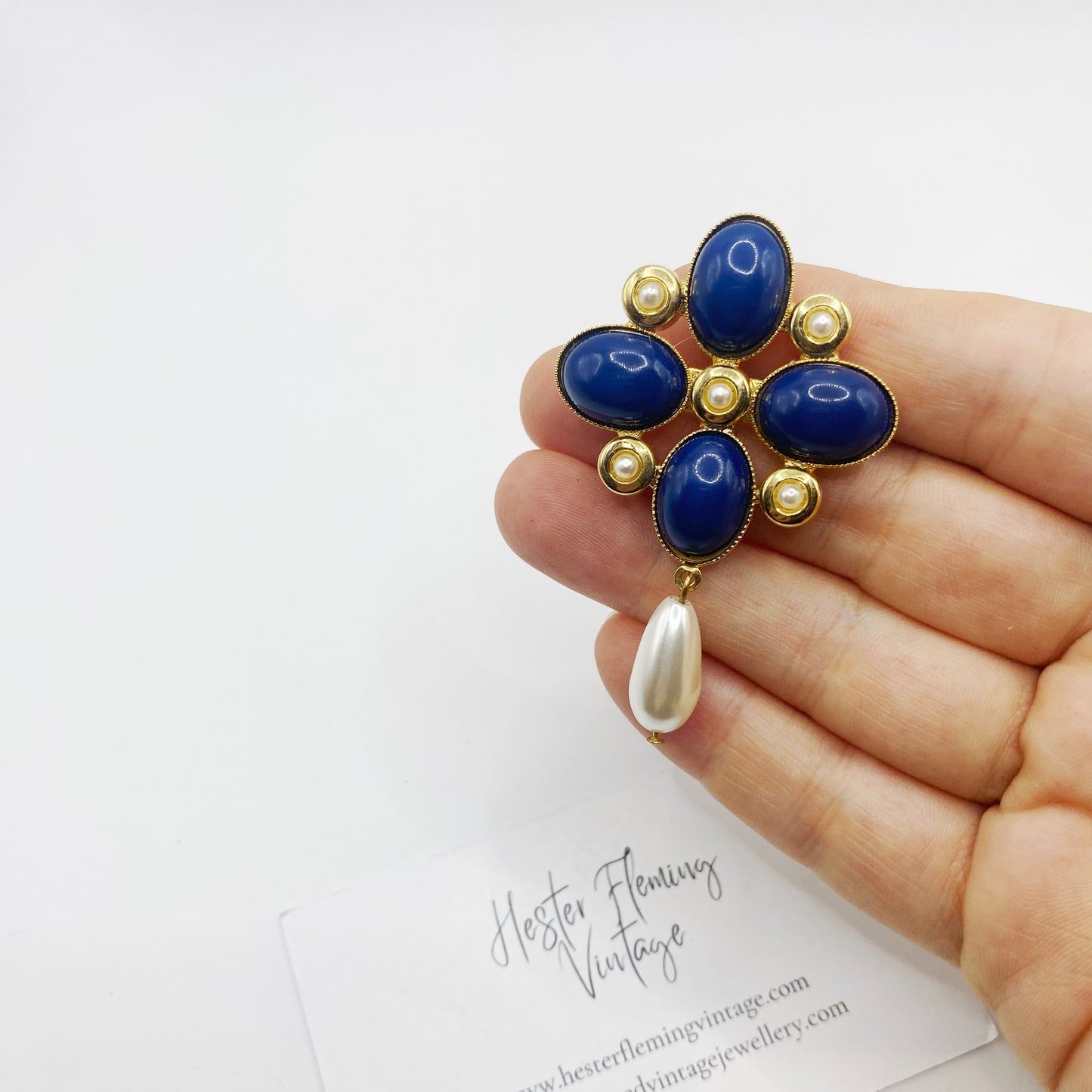 Scale view of 1990s Maltese cross brooch with pearl drop shown in hand for size reference