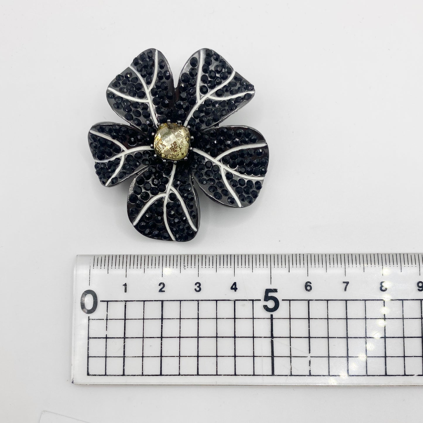 1990s Napier black crystal flower brooch shown next to a ruler for scale.