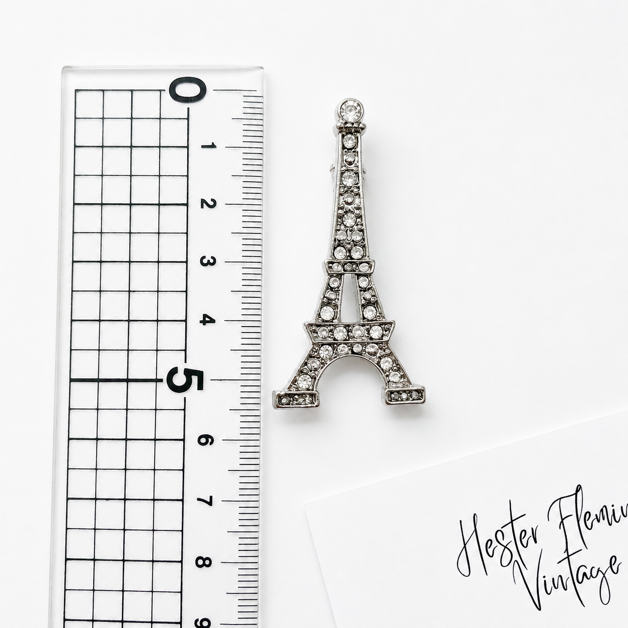 Vintage 90s Eiffel Tower Brooch, placed next to a ruler for measurement. 