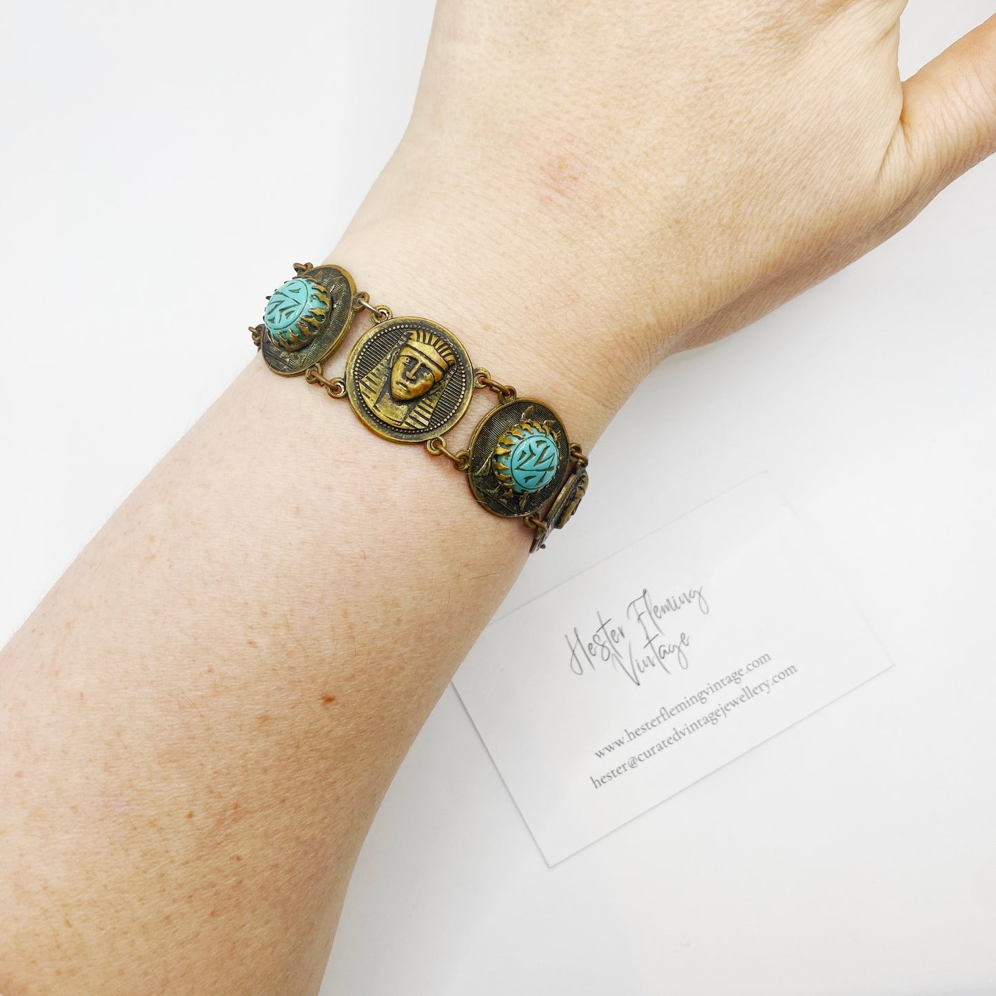 Styled image of antique Egyptian Revival bracelet with turquoise glass stones on wrist for display.