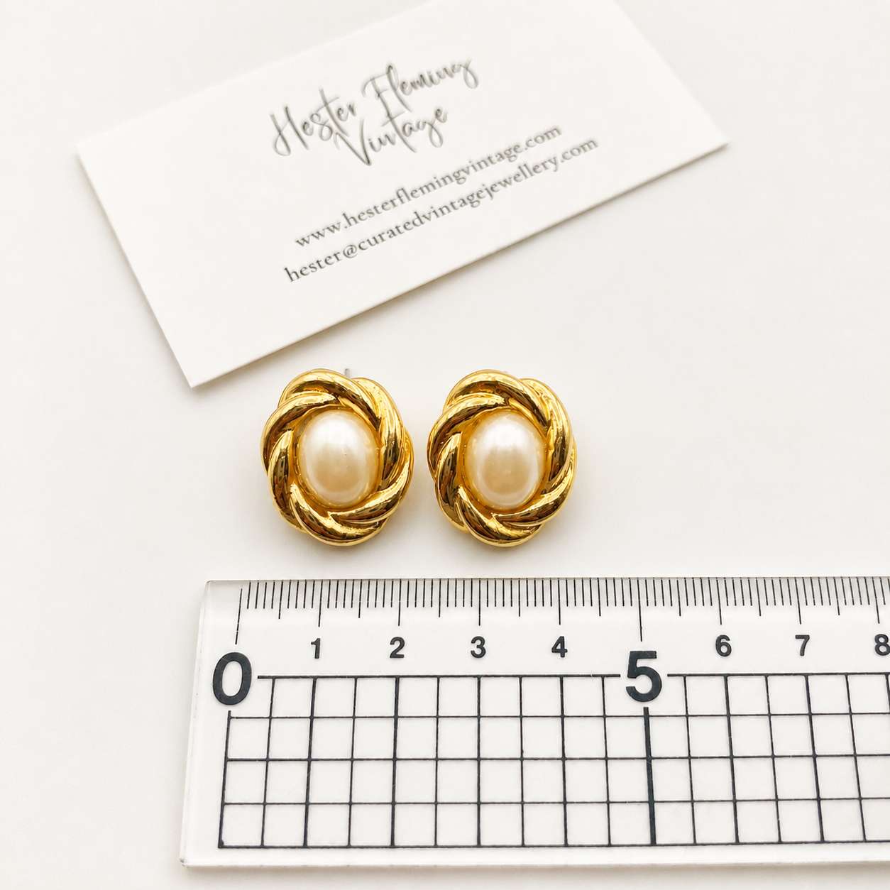 1980s Gilt knot and pearl earrings, next to a ruler, for measurement.