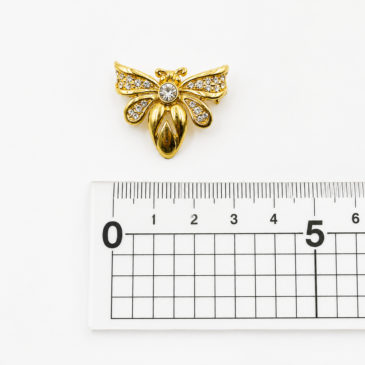 Vintage 1990s swarovski crystal bee brooch, placed next to a ruler for size. 
