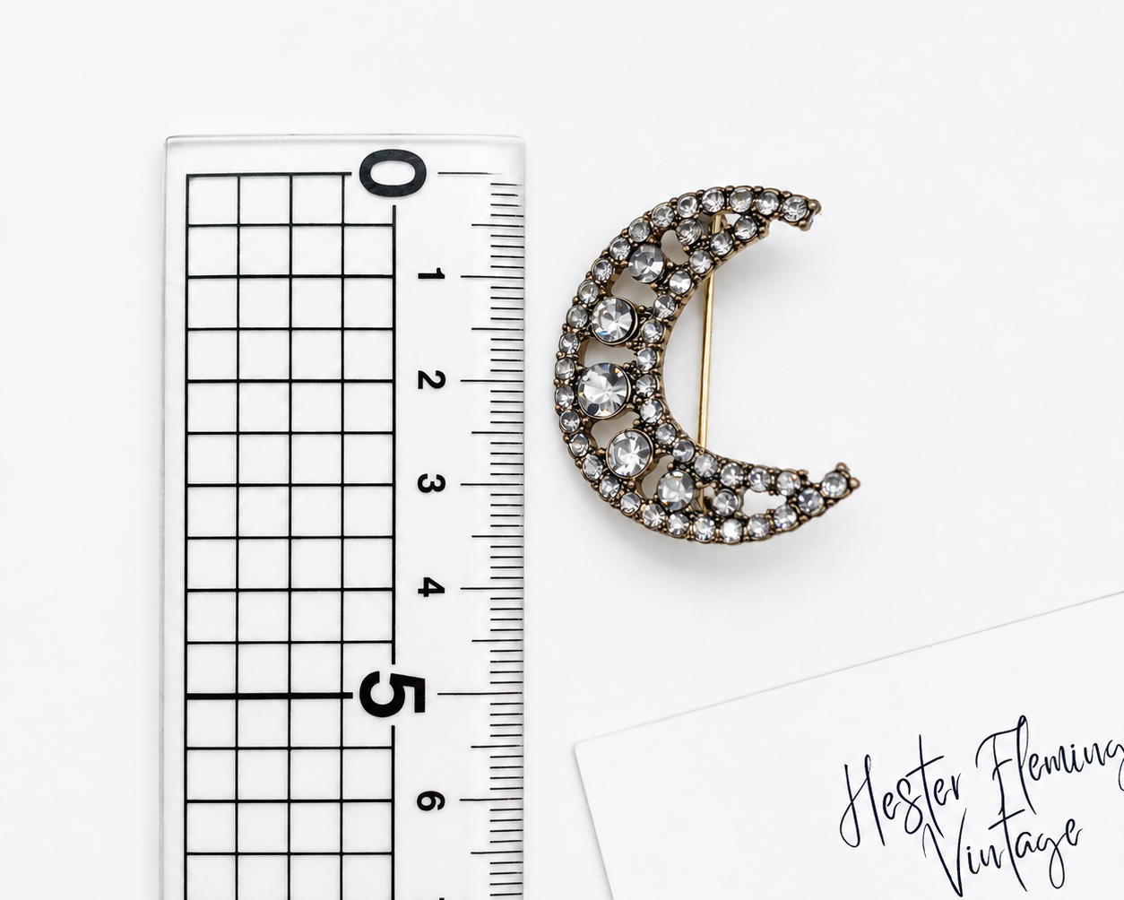 Crescent Moon Brooch, placed next to a ruler for size. 