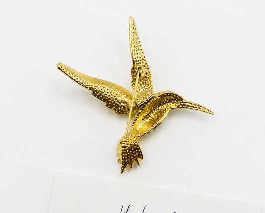 Back of gold hummingbird brooch on a white background with 'Hester Fleming Vintage' branding.