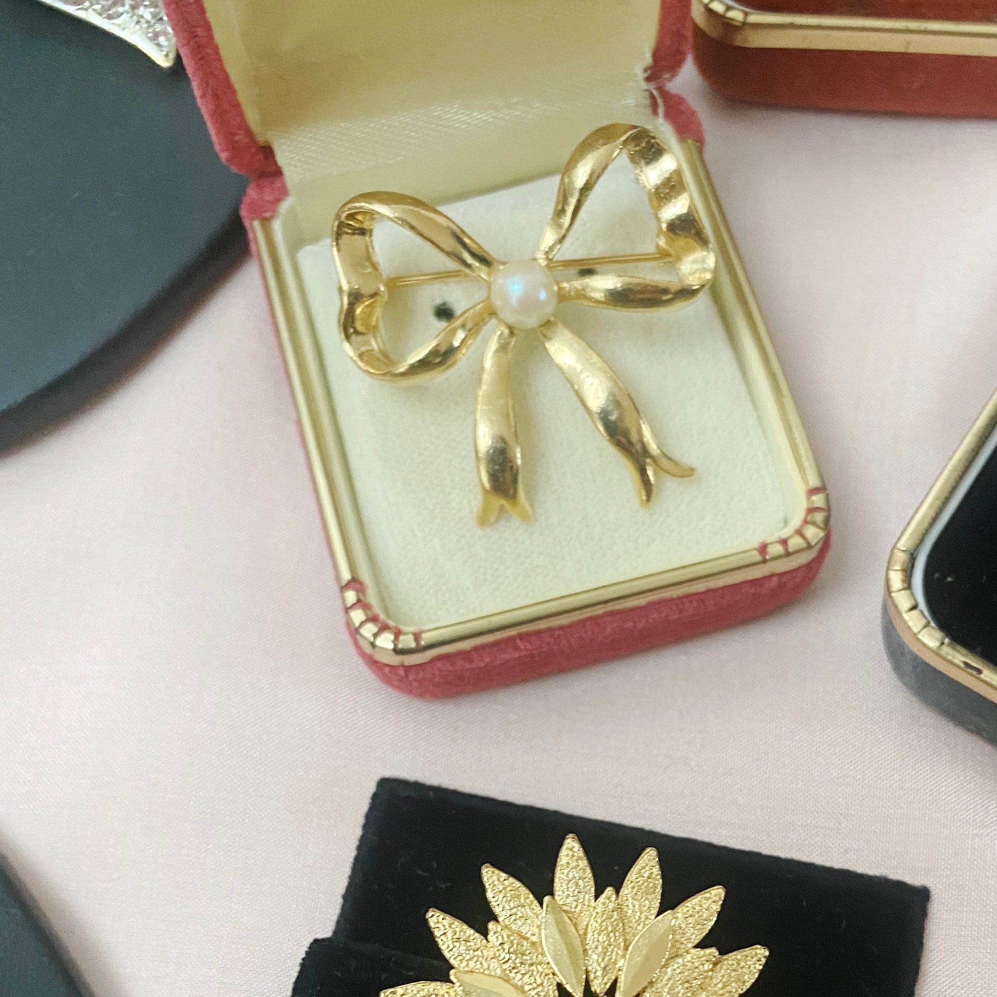 Vintage goldtone ribbon brooch with faux pearl centre, late 1980s style.