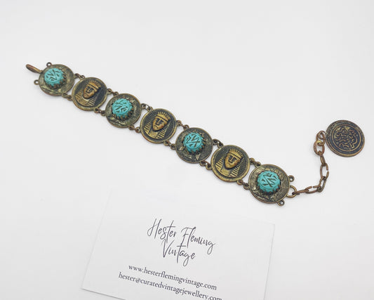 Full-length image of 22cm antique Egyptian Revival turquoise and brass bracelet laid flat.