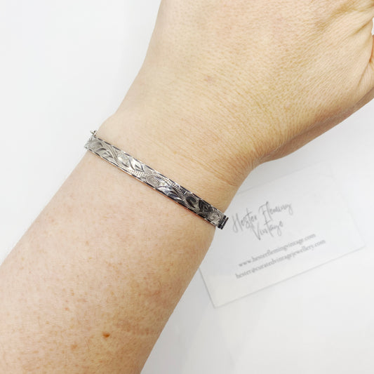 Birmingham sterling silver engraved hinged bangle worn on wrist showing slim oval profile