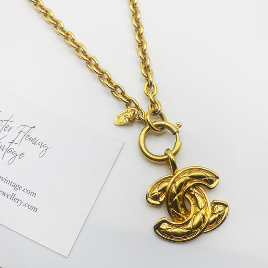 Close-up of signed 1980s Chanel logo pendant showing gold tone finish and Made in France signature.