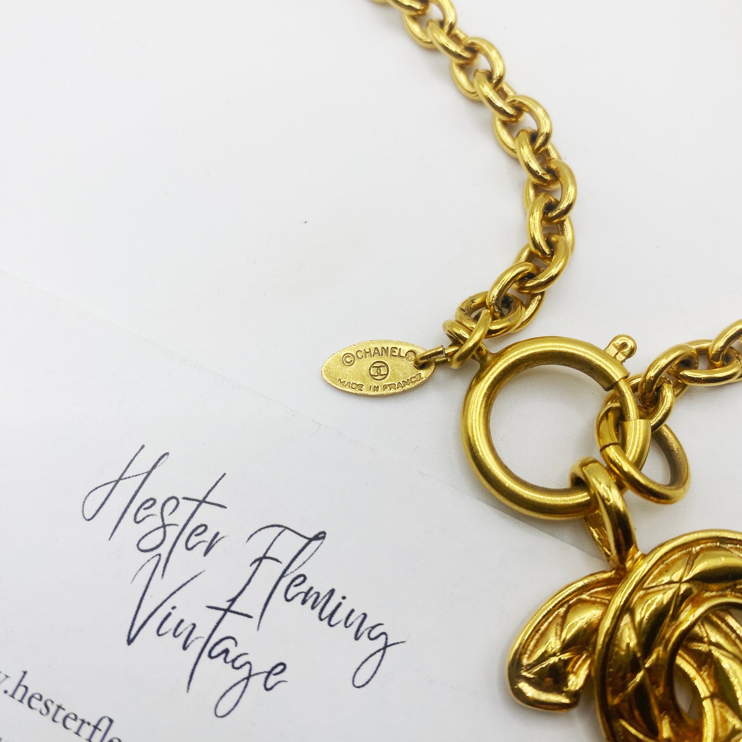 Close-up of signed 1980s Chanel logo pendant showing gold tone finish and Made in France signature.