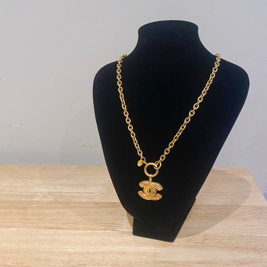 1980s Chanel logo pendant on chain, showing scale and wearability on jewellery stand. 