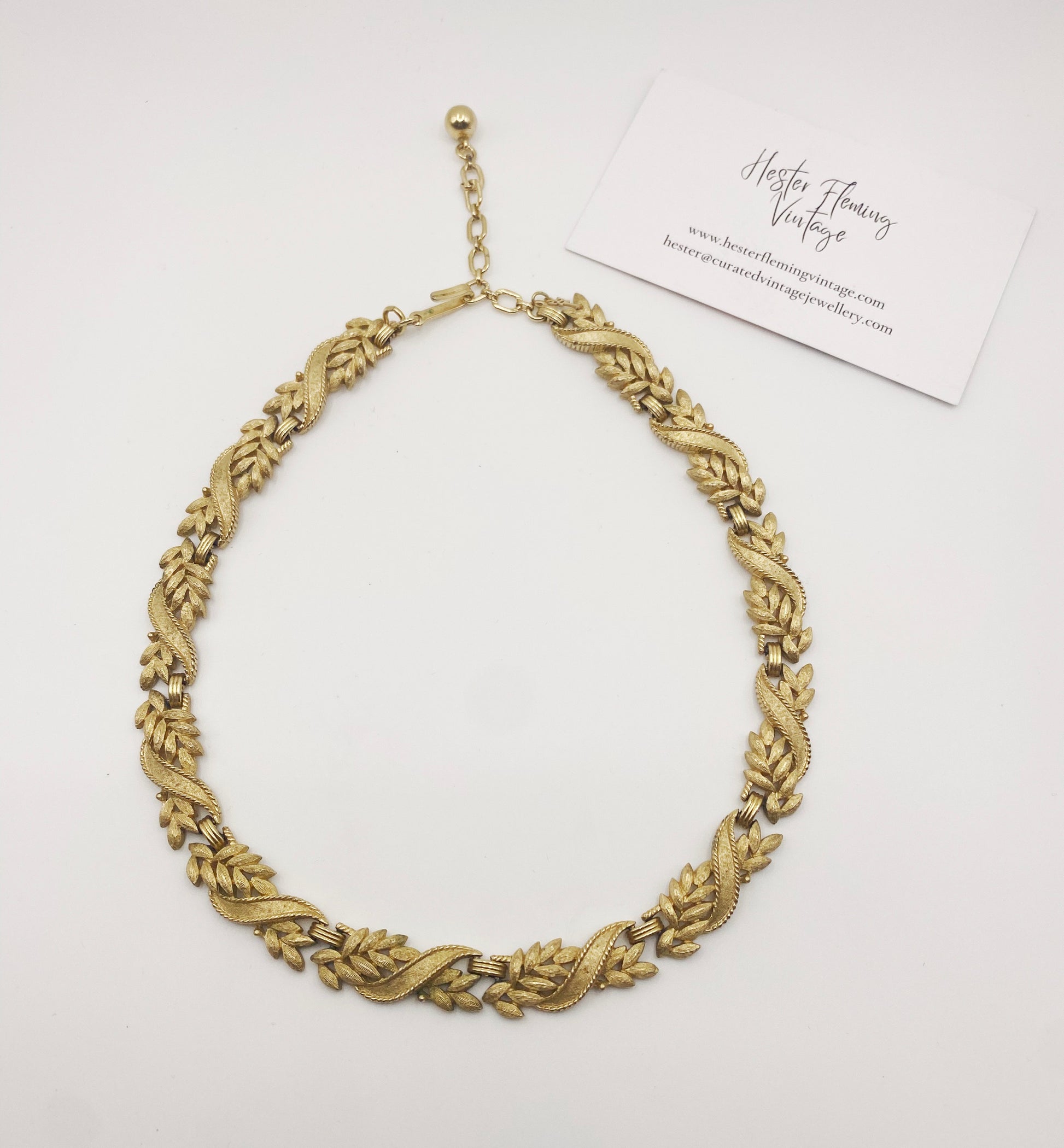 Flat lay of vintage Crown Trifari gold-tone necklace, collectible mid-century jewellery.