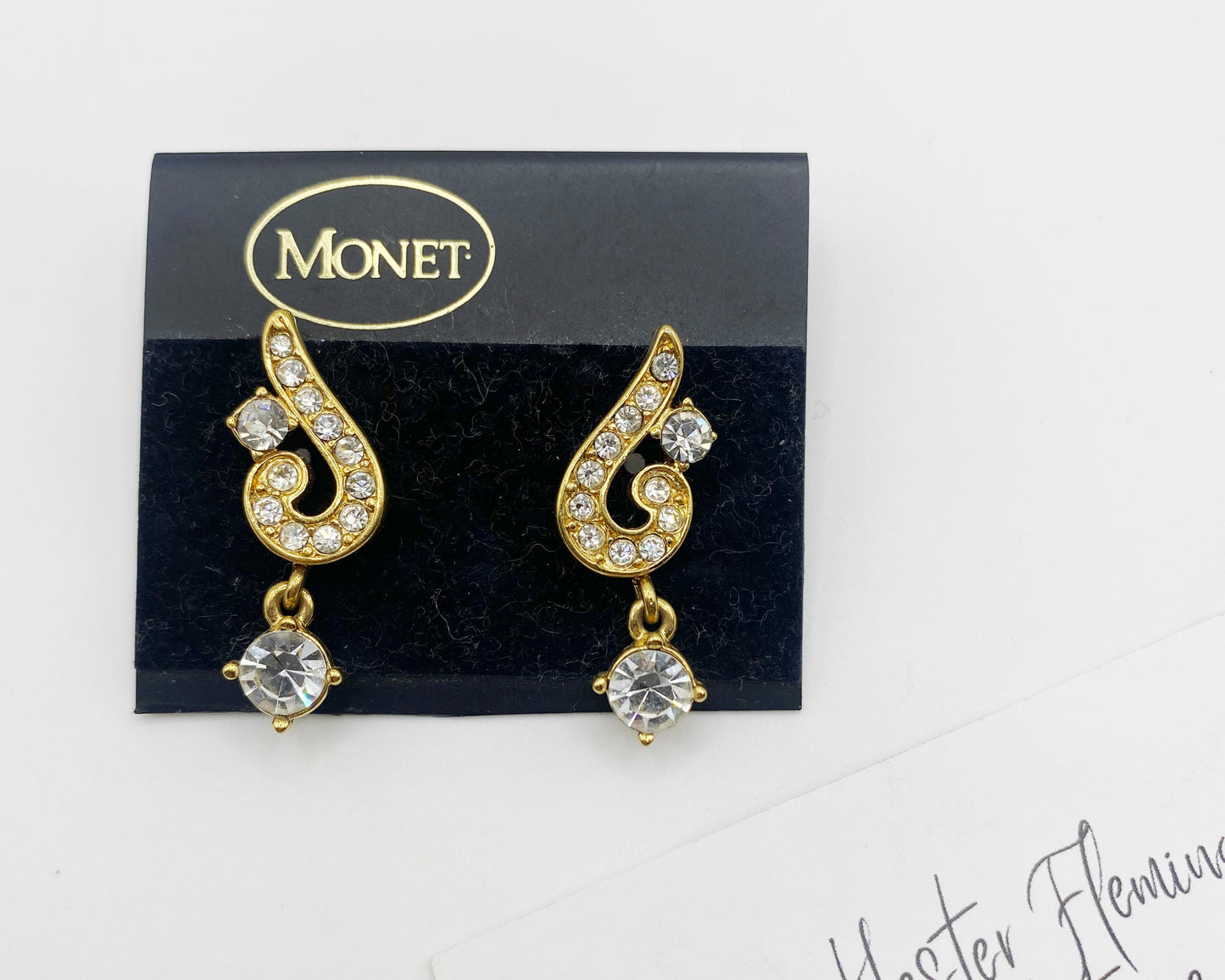 Front view of 1990s Monet gold-tone rhinestone swirl drop earrings on original card