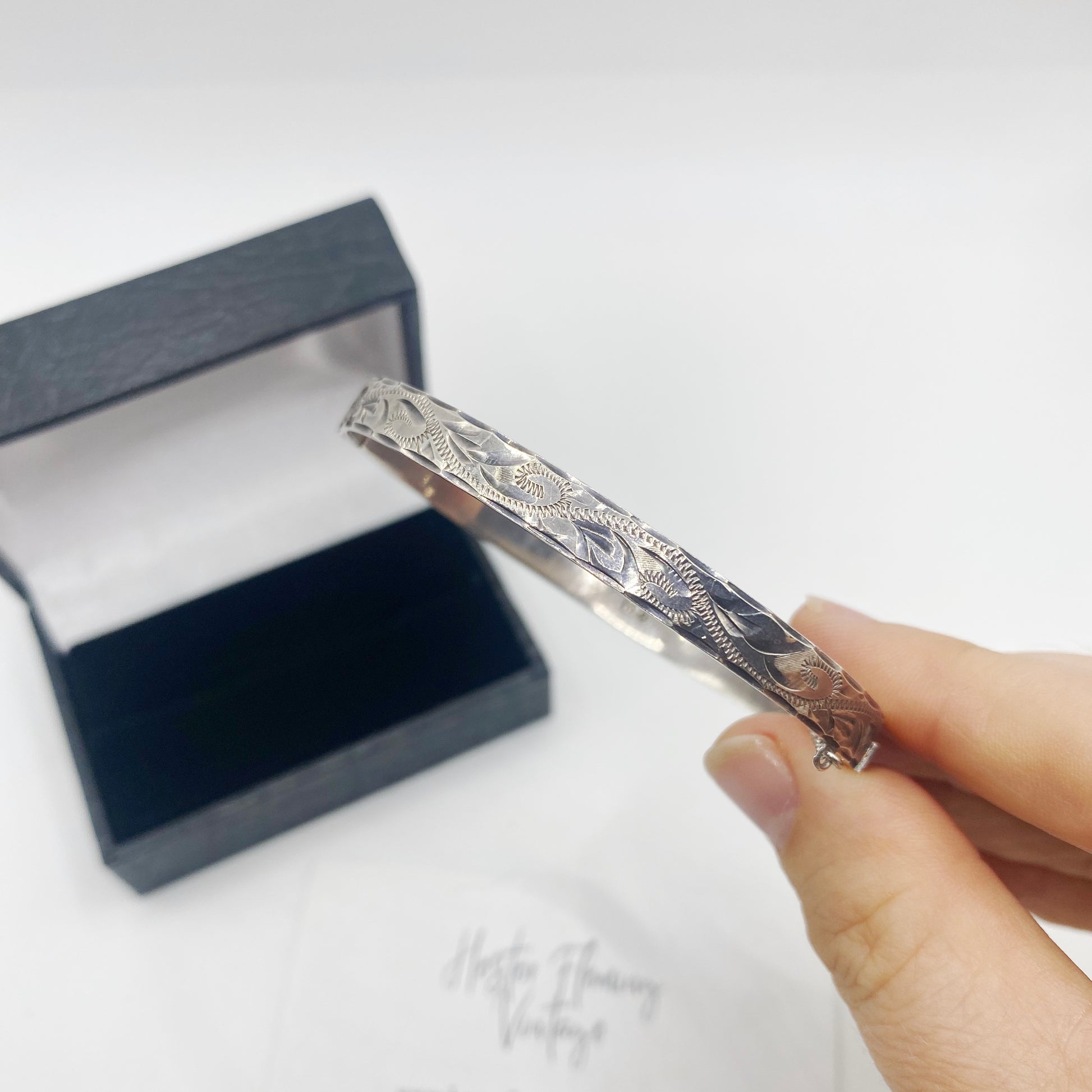 Close-up of engraved sterling silver hinged bangle with traditional British bright-cut pattern