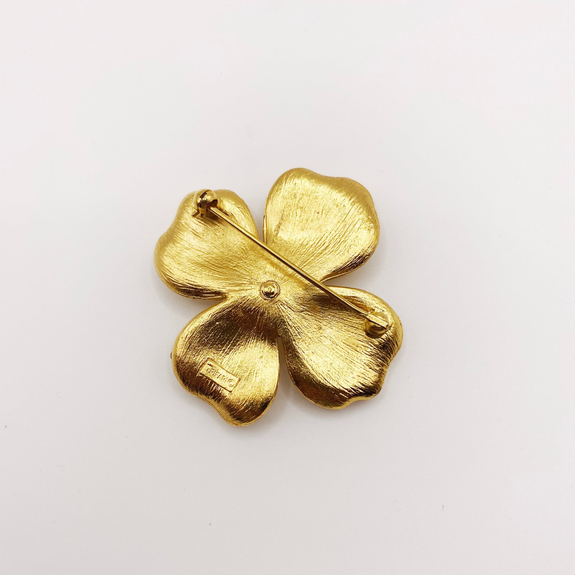 Back of vintage Trifari signed gold flower brooch with clasp detail.