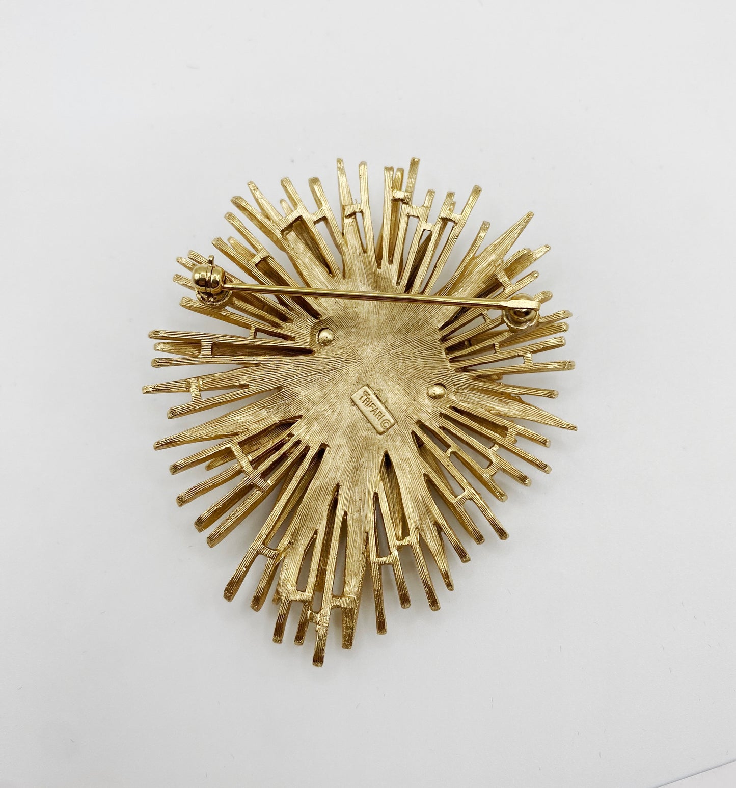 Back view showing signed Trifari hallmark on vintage starburst brooch