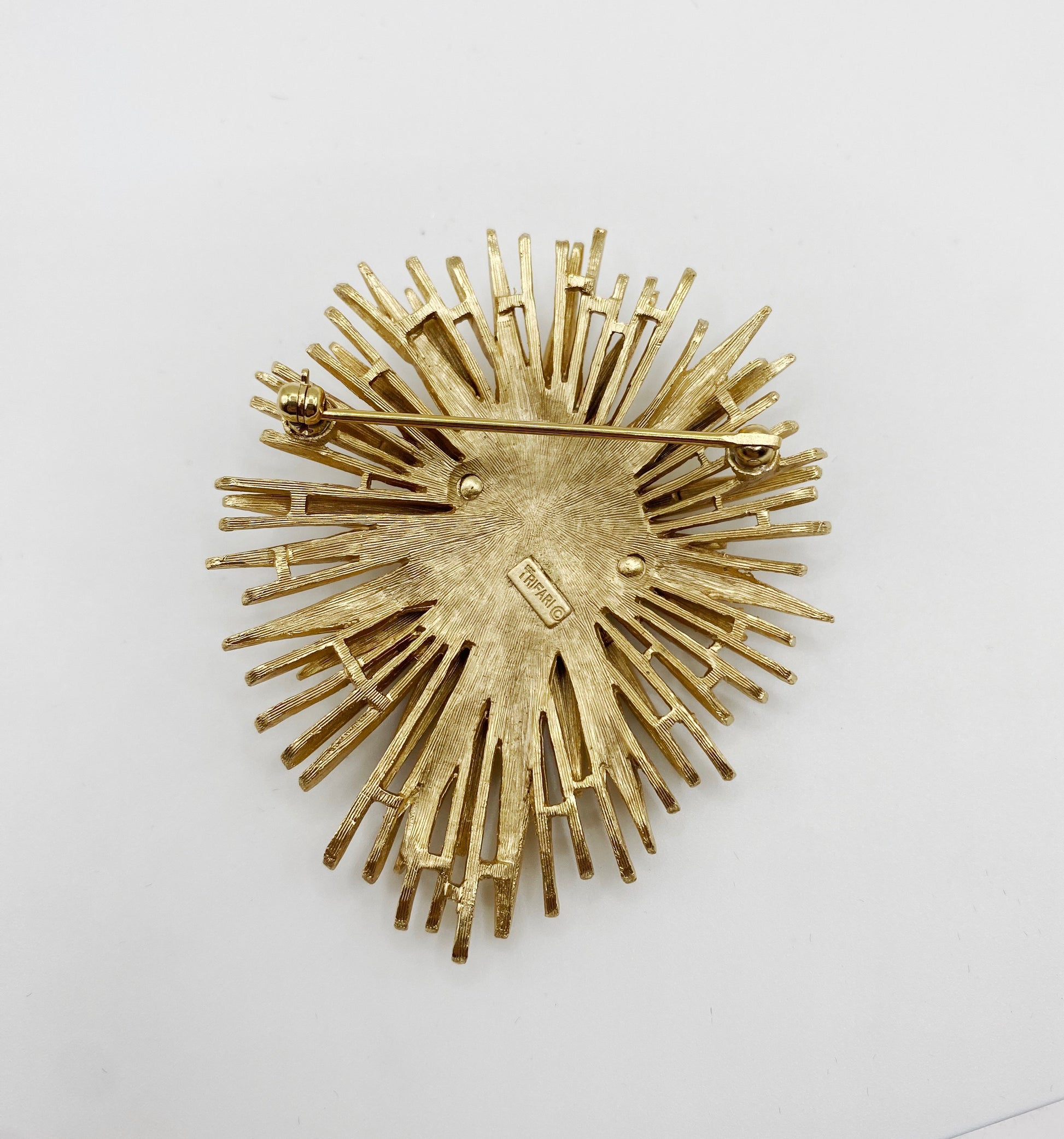 Back view showing signed Trifari hallmark on vintage starburst brooch