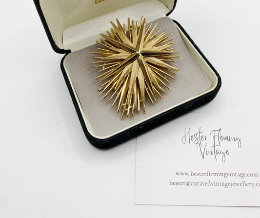 Front view of 1955–1969 vintage Trifari starburst brooch in gilt metal in display box. 