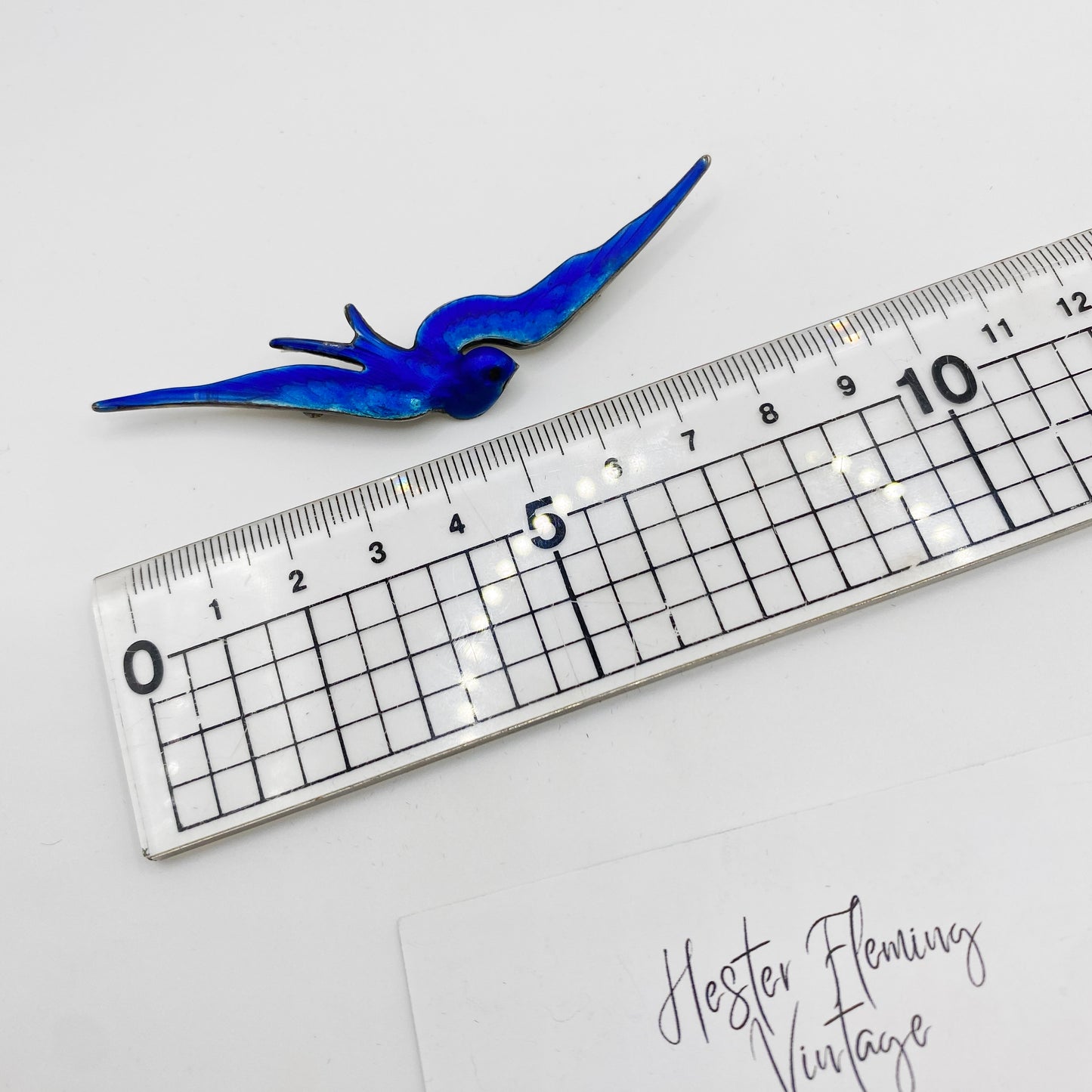 Victorian blue enamel swallow brooch in sterling silver shown beside ruler for size reference