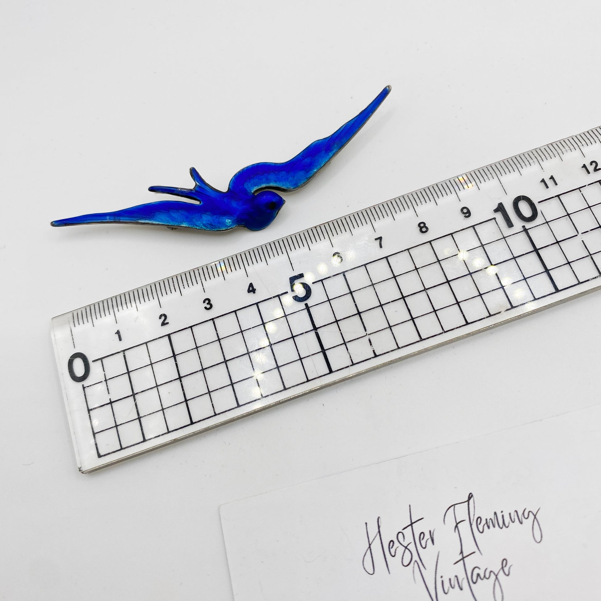 Victorian blue enamel swallow brooch in sterling silver shown beside ruler for size reference