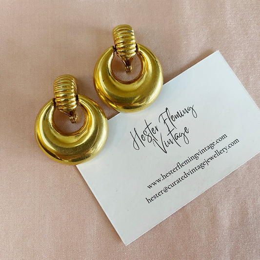 Front view of vintage 1970s Monet doorknocker earrings in gold plate, signed