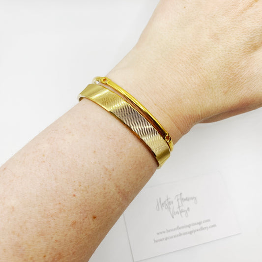 Vintage 1970s Monet gold bangle bracelet set in textured gold plating, signed Monet M, medium size.