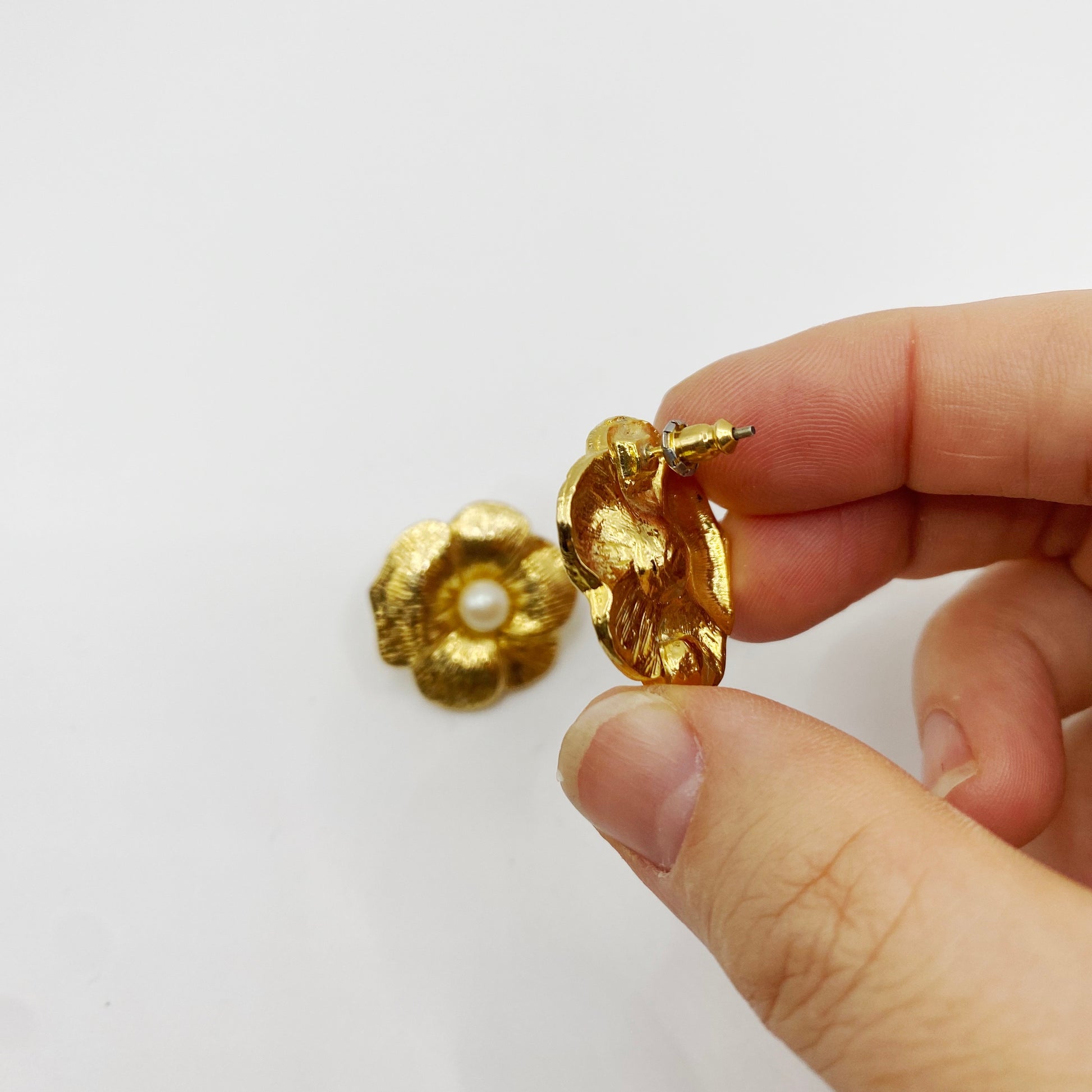 Vintage 1990s Monet gold and faux pearl earrings for pierced ears.  Showing fitting. 