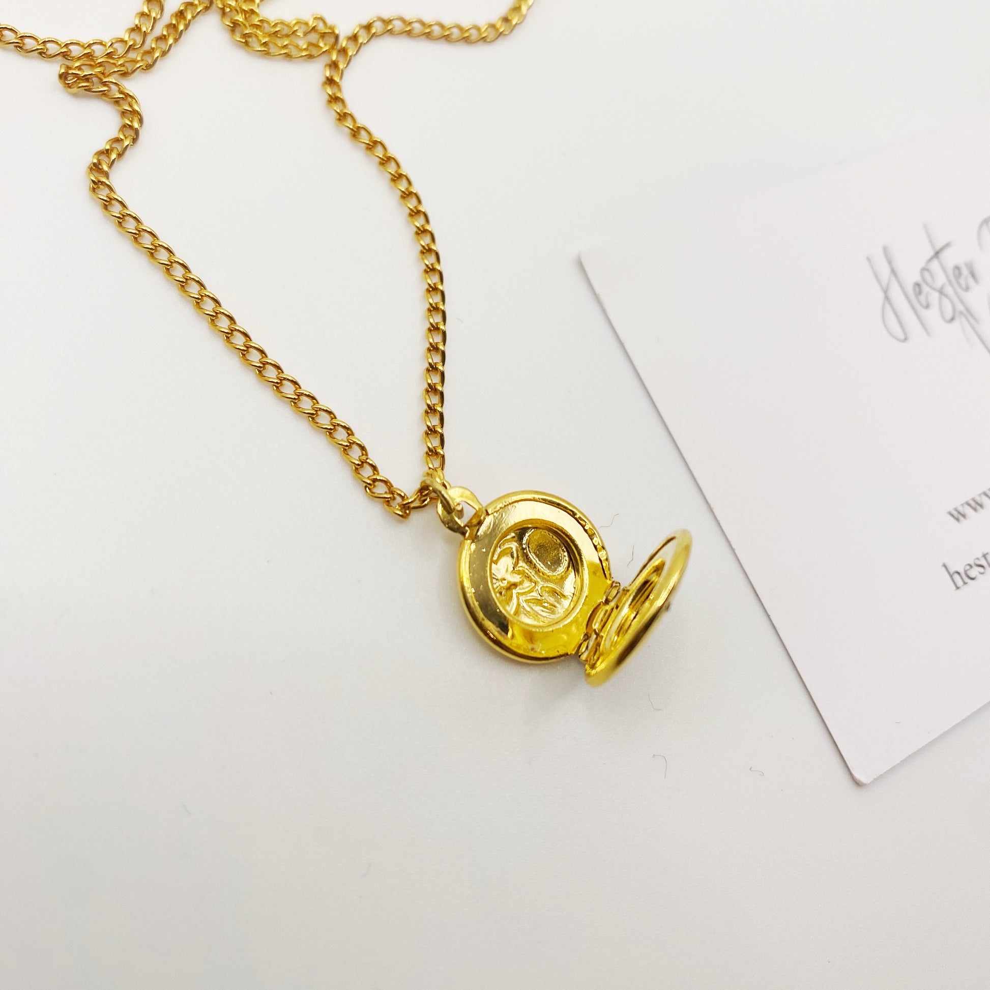 Collectible 1990s gold charm necklace with tiny locket pendant open view.