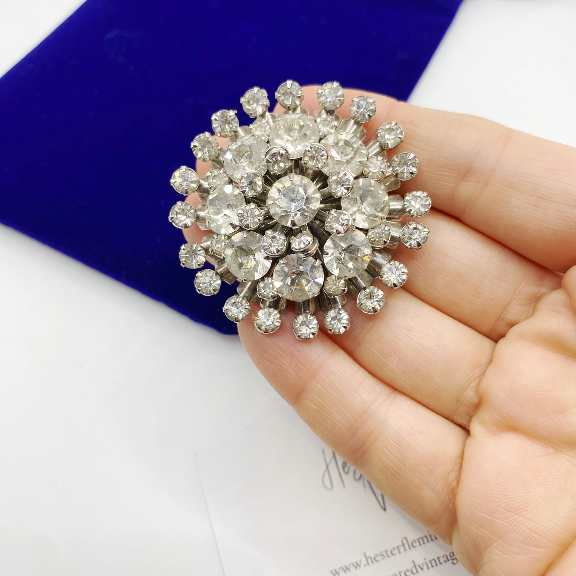 1950s rhinestone brooch held in hand showing scale.